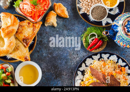 Orientalische und im Nahen und Mittleren Osten essen Konzept. Plov, samsa, Fladenbrot, Gewürze, grüner Tee auf blauem Hintergrund. Ansicht von oben und flach. Stockfoto
