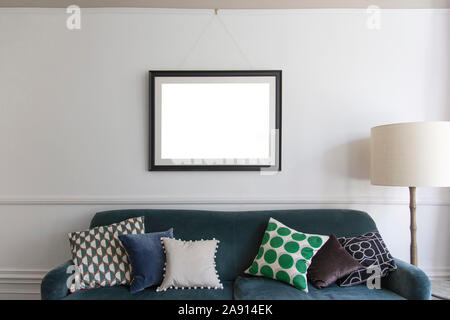 Leeren Bilderrahmen über ein blaues Sofa im Wohnzimmer aufhängen Stockfoto