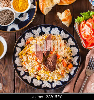 Orientalische und im Nahen und Mittleren Osten essen Konzept. Plov, samsa, Fladenbrot, Gewürze, grüner Tee auf Holz- Hintergrund. Ansicht von oben und flach. Stockfoto