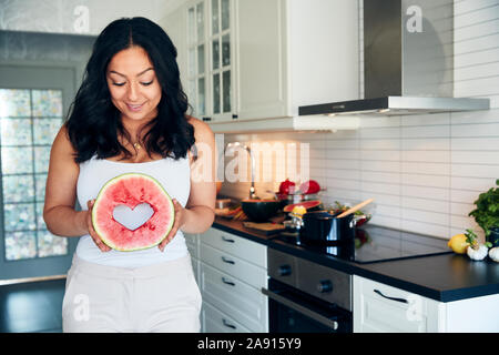 Die Frau in der Küche holding Wassermelone Stockfoto