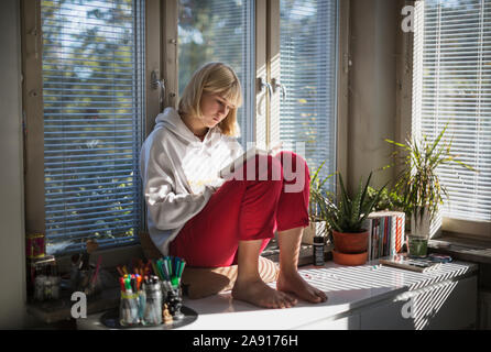 Junges Mädchen sitzt auf Schreibtisch Stockfoto