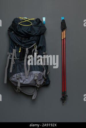 Nordic Walking Stöcke hängen an einer grauen Wand mit einem Rucksack zum Wandern. Konzept des gesunden Lebens. Stockfoto