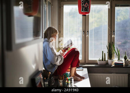 Junges Mädchen sitzt auf Schreibtisch Stockfoto