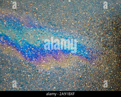 Eine Pfütze von Benzin auf dem Bürgersteig. Close-up. Benzin, auf dem nassen Asphalt zugespielt hatte. Bunte Benzin, auf dem nassen Asphalt ins Sekundaersystem gelangt Stockfoto