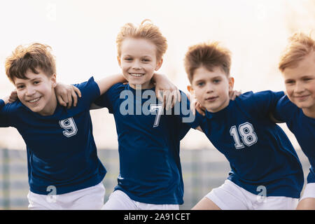 Gerne Freunde auf eine Fußballmannschaft. Die jungen Sportler, die Spaß haben. Kinder Fussball Spieler jubeln zusammen Stockfoto