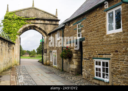 Old Stone Cottages auf gepflasterten Straße führenden gewölbten gateway Eingang zum Schloss zu öffnen. Oakham, Rutland, England, Großbritannien, Großbritannien Stockfoto