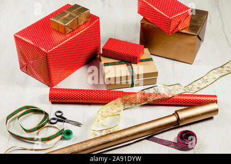 Verpackung Weihnachtsgeschenke in Papier Konzept. Menge Kartons, Bänder, Schere, Klebeband auf weißem Holzfußboden. Stockfoto