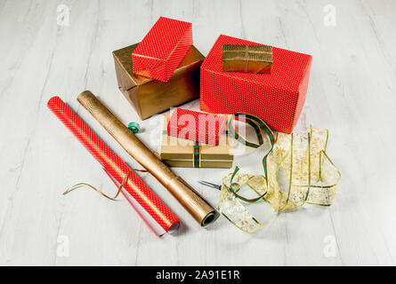 Verpackung Weihnachtsgeschenke in Papier Konzept. Menge Kartons, Bänder, Schere, Klebeband auf weißem Holzfußboden. Stockfoto