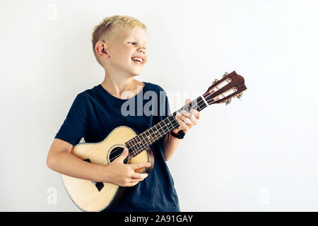 Blonde junge Teenager spielt Ukulele und singt ein lustiges Lied. Stockfoto