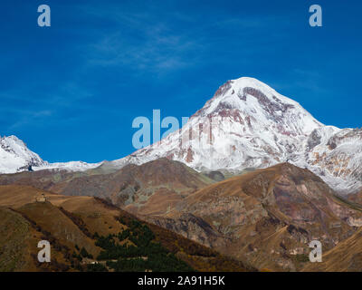 Georgien: Mt. Kazbag, mit gergeti Kloster der Heiligen Dreifaltigkeit, von Stephantsminda. Die hohen Kaukasus, die georgische Armee Straße. Stockfoto