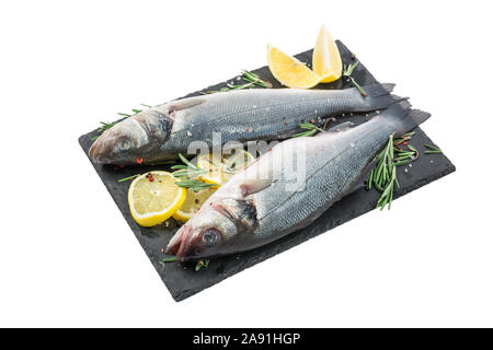 Frischer Fisch Wolfsbarsch und Zutaten zum Kochen, Zitrone, Pfeffer und Rosmarin auf schwarzem Schiefer auf weißem Hintergrund. Nach oben Schließen Stockfoto