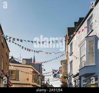 Bunting zwischen shop Fronten in einer belebten Straße in Tenby, Pembrokeshire, Wales, Großbritannien Stockfoto