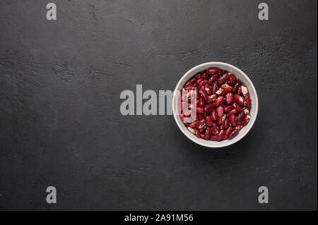 Schale mit roten Bohnen auf ein strukturiertes Holz- schwarzen Hintergrund. Pflanzliches Eiweiß gesunde Ernährung Stockfoto