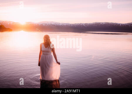Frau in See bei Sonnenuntergang Stockfoto