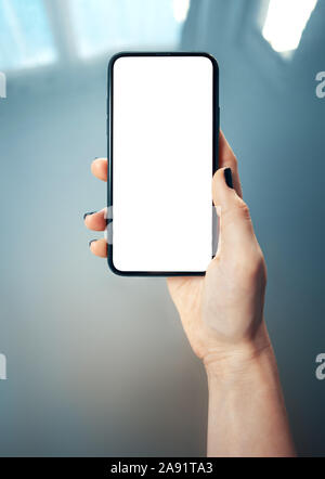 Mockup Bild der Frau hand mit dünnen Rahmen Handy mit leerer Bildschirm in glänzend und blurry Unternehmensumgebung - Bild Stockfoto