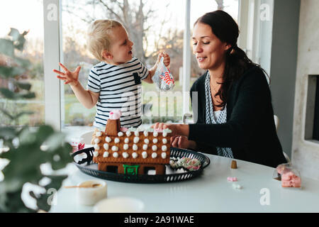 Mutter mit Sohn dekorieren Gingerbread House Stockfoto