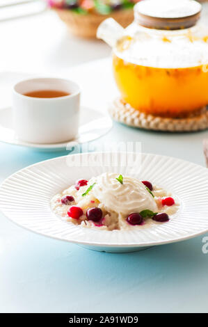 Rice Porridge mit Milch und Cranberry in einer Platte auf einen Tisch. Frühstück und gesunde Mahlzeit Konzept. Stockfoto