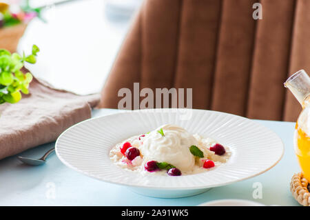 Rice Porridge mit Milch und Cranberry in einer Platte auf einen Tisch. Frühstück und gesunde Mahlzeit Konzept. Stockfoto