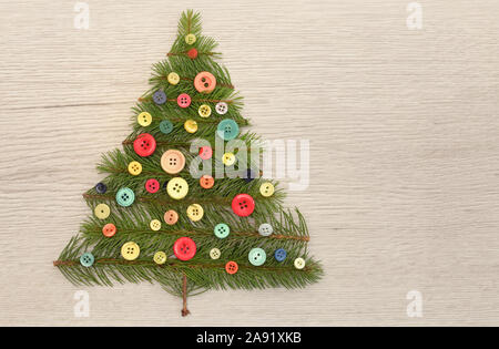 Weihnachtsbaum mit Kiefernzweigen und Tasten auf hölzernen Tisch Stockfoto