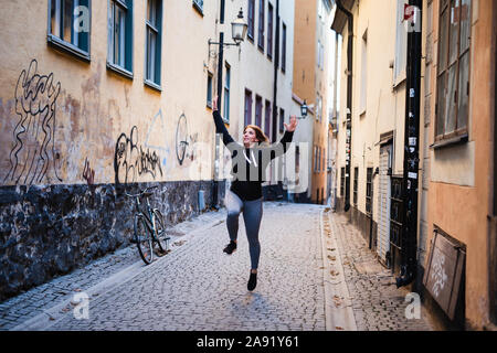 Frau springen auf schmale Straße Stockfoto