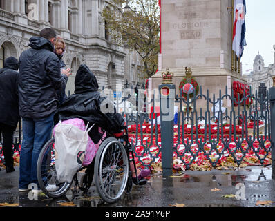 Westminster, London, Großbritannien. November 2019. An einem nassen regnerischen Nachmittag in London kommen Menschen und zollen gefallenen Helden im Cenotaph Tribut, wo noch Kränze aus den Wochenendzeremonien gesammelt werden. Stockfoto