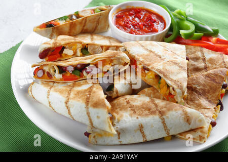 Close-up von Gegrilltem mexikanischen chicken Quesadillas mit Gemüse, shredded Cheddar Käse, Oliven und Champignons auf einem weißen Teller mit Tomaten Salsa, vie Stockfoto