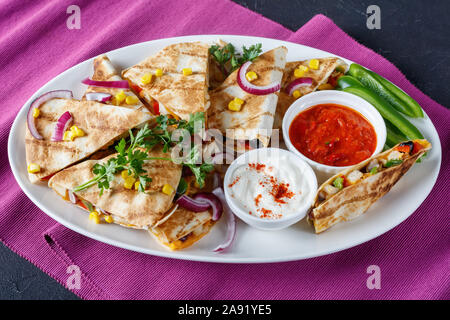 Mexikanischen Chicken Quesadilla mit Gemüse, Maiskörner, shredded Cheddar Käse, Oliven und Champignons auf eine weiße, ovale Servierplatte mit Tomate Salsa und Stockfoto
