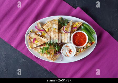 Mexikanischen chicken Quesadillas mit Gemüse, Maiskörner, shredded Cheddar Käse, Oliven und Champignons auf eine weiße, ovale Platte mit Tomaten Salsa, vi Stockfoto