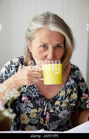 Ältere Frau aus der Tasse trinken Stockfoto