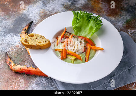 Close-up-Salat mit Schnee Krebsfleisch, Avocado und Gemüse. Serviert auf einem grauen Serviette und eine rostige Hintergrund Stockfoto