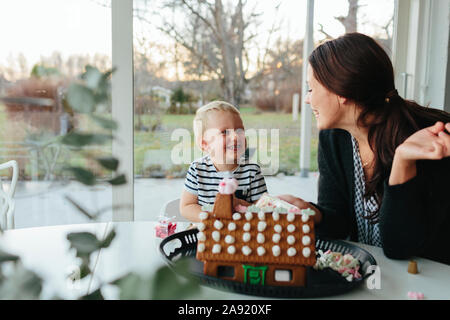 Mutter mit Sohn dekorieren Gingerbread House Stockfoto