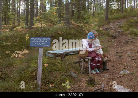 Schwestern sitzt auf der Bank im Wald Stockfoto