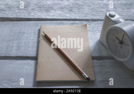 Blick von oben auf die Class Zimmer in Natur Hintergrund mit braunen Bücher, Bleistifte, Wecker, auf einem weißen Holztisch. Stockfoto