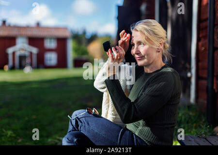 Lächelnde Frau, die selbst im Spiegel prüfen Stockfoto