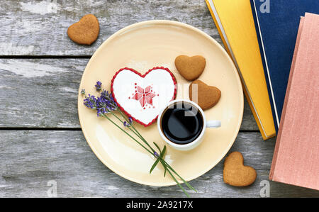 Herzförmige Honigkuchen mit slawischen Muster und Cookies, eine Tasse Kaffee, frischem Lavendel, Shell und Bücher sind in der Nähe auf Holztisch, Flach, oben Stockfoto