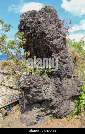Black Rock aus erstarrter Lava. Abstrakte Form der riesigen schwarzen Stein. Verdorrte Vegetation aufgrund der tropischen Sonne. Speer Boulder. Stockfoto