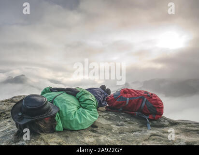 Junge Frau einschlafen, nachdem gerade nebligen Landschaft, Outdoor posieren. Rest auf mountainsummit. Aktiver Lebensstil Konzept. Stockfoto