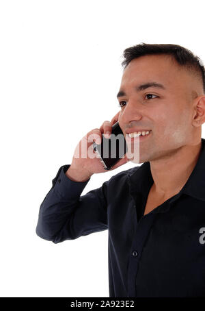Ein Lächeln, glücklich, junger Mann in einem schwarzen T-Shirt stand im Studio mit seinem Handy am Ohr und sprechen, auf weißem Hintergrund Stockfoto