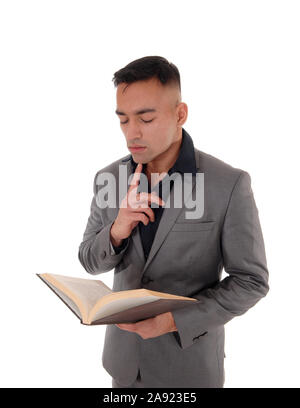 Ein junger hübscher ost-indischen Mann in einem grauen Anzug mit einem Buch in seinen Händen, Lesen, auf weißem Hintergrund Stockfoto