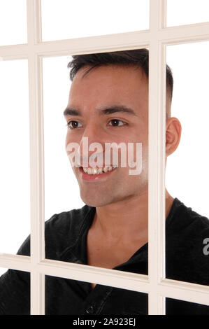 Ein glückliches ost-indischen Mann stand hinter einer weißen Fensterrahmen in einem schwarzen Kleid Shirt mit einem großen Lächeln, auf weißem Hintergrund Stockfoto