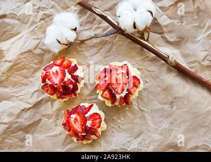 Schöne Muffin mit frischen Erdbeeren liegt auf Handwerk Papier, close-up. Stockfoto