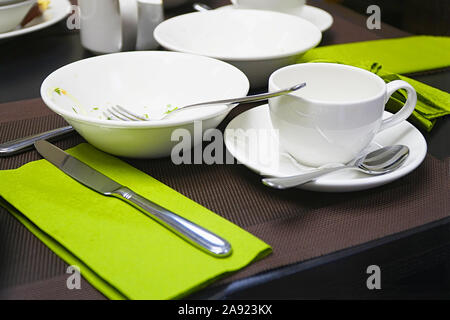 Benutztes Geschirr auf dem Tisch. Kaffee Tasse, Teller, Messer und Löffel auf dem Tisch. Selektiver Fokus Stockfoto