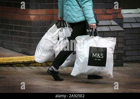 Eine Frau, die M & S Marks und Spencer Clothing Store Kunststoff Tragetasche 100 % aus recyceltem Kunststoff wiederverwendbar Supermarkt Taschen für das Leben Stockfoto