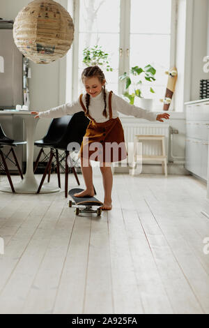 Mädchen auf Skateboard zu Hause Stockfoto