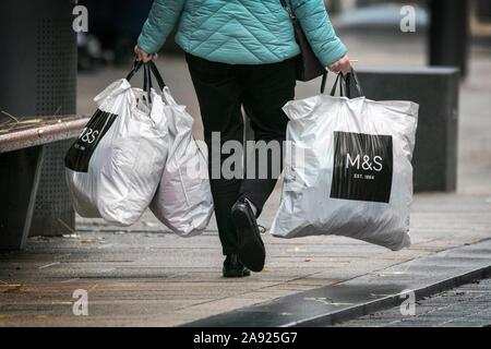 Eine Frau, die M & S Marks und Spencer Clothing Store Kunststoff Tragetasche 100 % aus recyceltem Kunststoff wiederverwendbar Supermarkt Taschen für das Leben Stockfoto