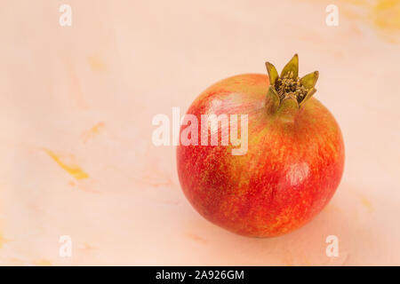 Eine rote reife Granatapfel auf einem rosa Hintergrund Stockfoto
