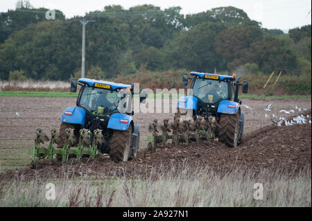 Blau New Holland T7 Traktoren, Pflügen und Säen, der Saatgut in einem Feld auf Hayling Island England Stockfoto