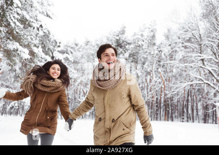 Freundliche Paar Wandern durch den Winterwald, Hände halten Stockfoto