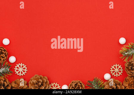 Traditionelle Weihnachten flach Hintergrund mit verschneiten Tannenzweigen, Tannenzapfen und Holz- Schneeflocken um unteren Rand Stockfoto