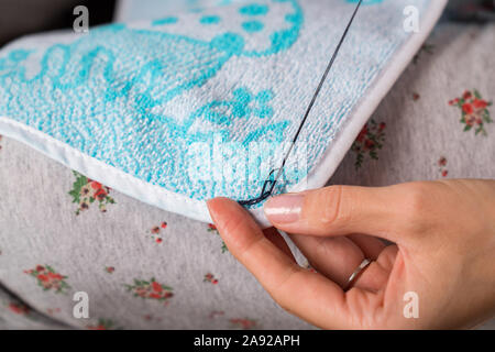 Frau näht bis Kleidung. Hände Näherin close-up. Ausbessern von Kleidung. Stockfoto